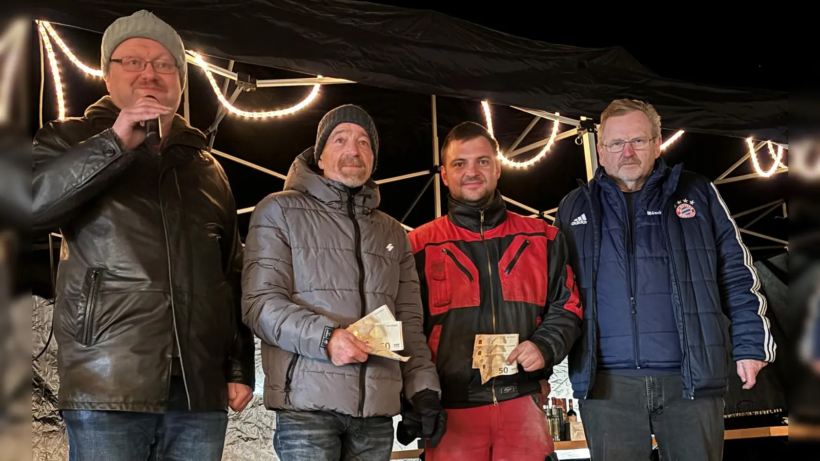 Bild v.r.: Weihnachtsmarkt-Organisator Hermann Lühr übergibt die Spende an Johannes Großer und Michael Hörl, 1. Bürgermeister Uwe König führt am MIkrofon durch die Tombola. (Bild: Patrick Horn)