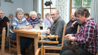 Aufmerksam schauen die Gäste dem Drehen des „Spinnrades“ zu, das von Lisa Rauh, 3. Bürgermeisterin von Friedenfels, betrieben und mit Schafwolle gefüttert wurde. <br> (Bild: Erwin Bächer)