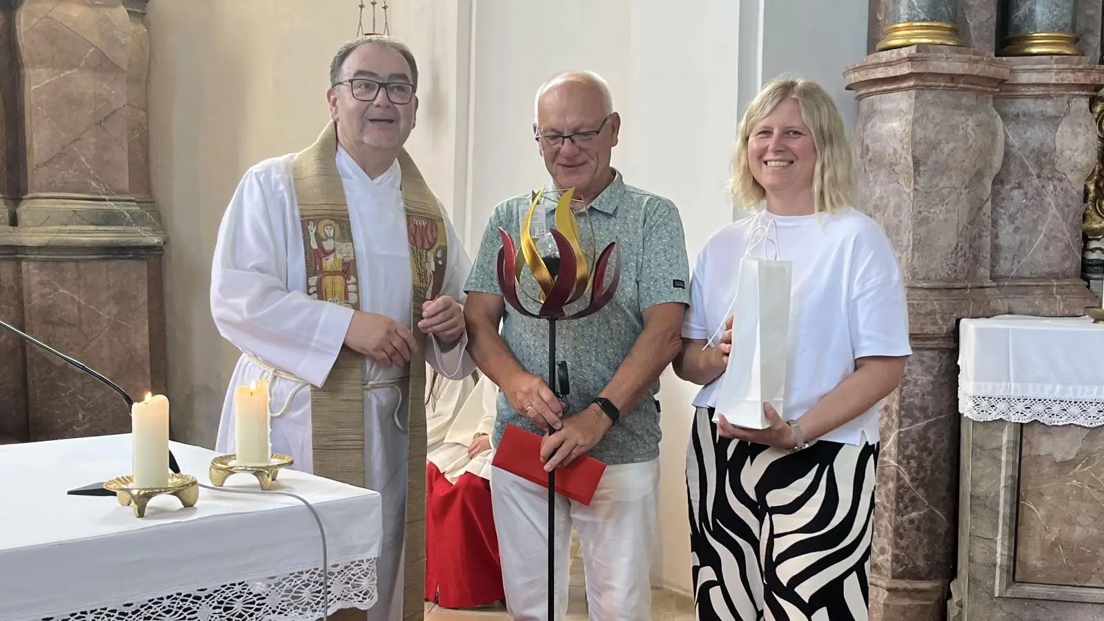 Kirchenpfleger Erich Weiß und Pfarrsekretärin Alexandra Deichler überreichen Herbert Mader die Geschenke des Pfarrgemeinderates und der Kirchenverwaltung (Bild: Dr. Martin Pöllath)