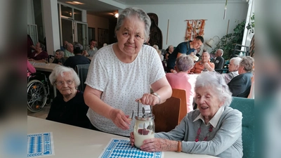 Bewohnerinnen rühren den Rahm im Butterfass (Bild: Sylvia Benjamin)