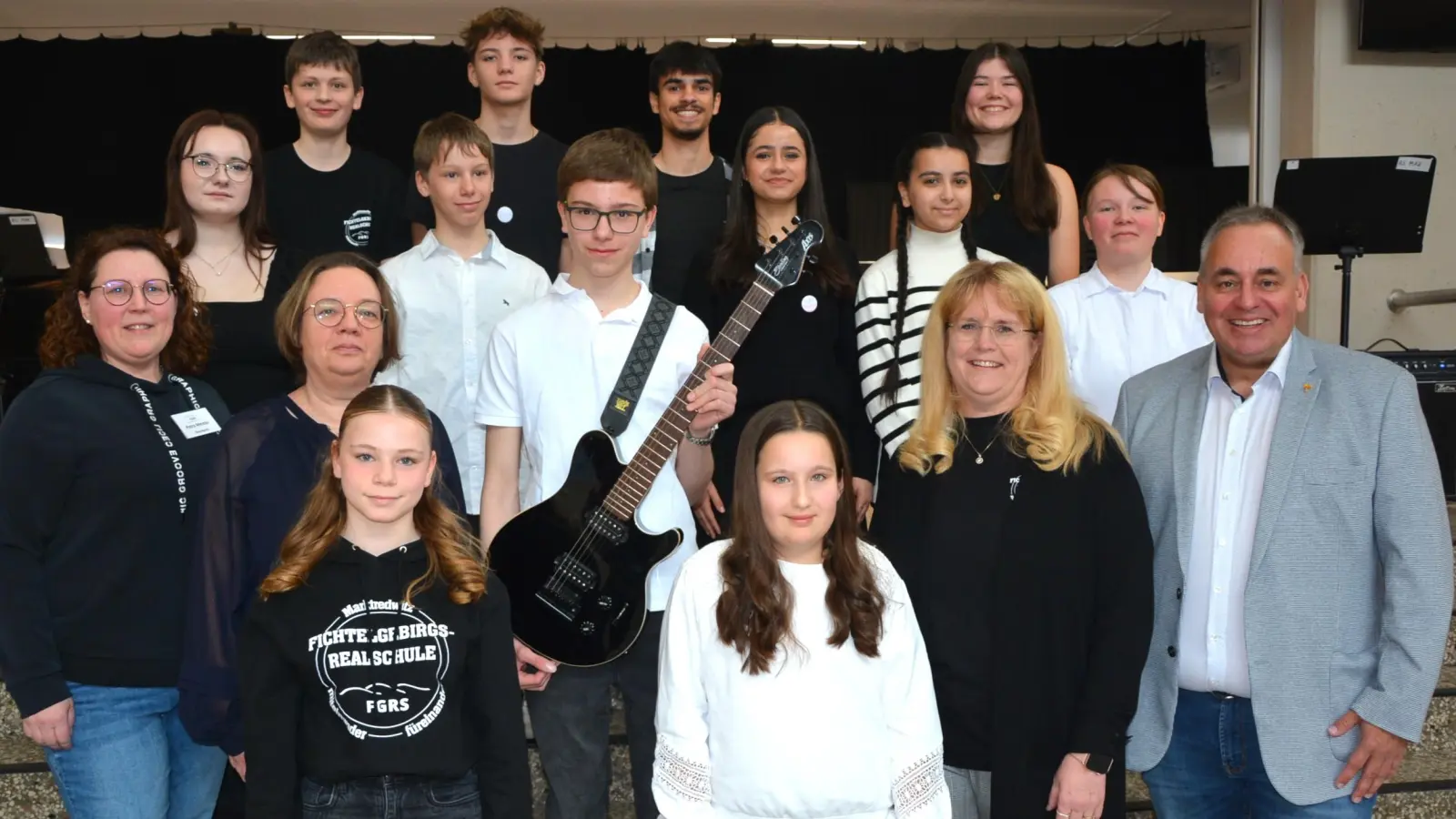 Große Freude bei der Schulband der Fichtelgebirgsrealschule Marktredwitz. Am Samstag erhielten sich aus der Hand vom Waldershofer KIBA-Team, mit Anja Friedrich (2. von rechts), sowie (2. Reihe von links) Petra Meister und Anke Weißenborn eine neue E-Gitarre im Wert von 650 Euro überreicht. Schulleiter Oliver Brandt (rechts) dankte dem KIBA-Team für diese tolle Geste.  (Bild: Josef Rosner)