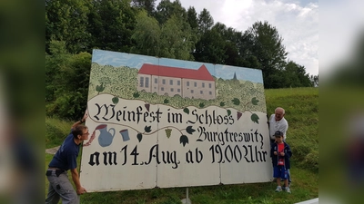  Am Ortseingang von Burgtreswitz lädt eine übergroße Tafel zum Weinfest ein. Die beiden Vorstandsmitglieder Andreas und sein Vater Josef Landgraf (von links) haben sie aufgestellt. Selbst der kleine Enkel half mit.  (Bild: Peter Garreiss)