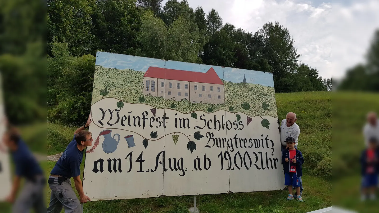  Am Ortseingang von Burgtreswitz lädt eine übergroße Tafel zum Weinfest ein. Die beiden Vorstandsmitglieder Andreas und sein Vater Josef Landgraf (von links) haben sie aufgestellt. Selbst der kleine Enkel half mit.  (Bild: Peter Garreiss)