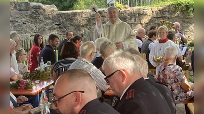 Pfarrer Adam Niecieki geht mit Ministranten Timo durch die Reihen um die Kräuterbüschel mit Weihwasser zu segnen. (Bild: Sieglinde Schärtl)