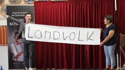 Wie&#39;s geht, weiß nur Marius Koslowski: Verblüfft sah Landvolkvorsitzende Rita Hey, dass der junge Pressather Zauberkünstler das Ergebnis einer Verknüpfung mehrerer Zufallszahlen richtig vorausgesagt hatte - und die errechnete Glückszahl zudem das Wort „Landvolk” wiedergab. (Bild: Bernhard Piegsa)