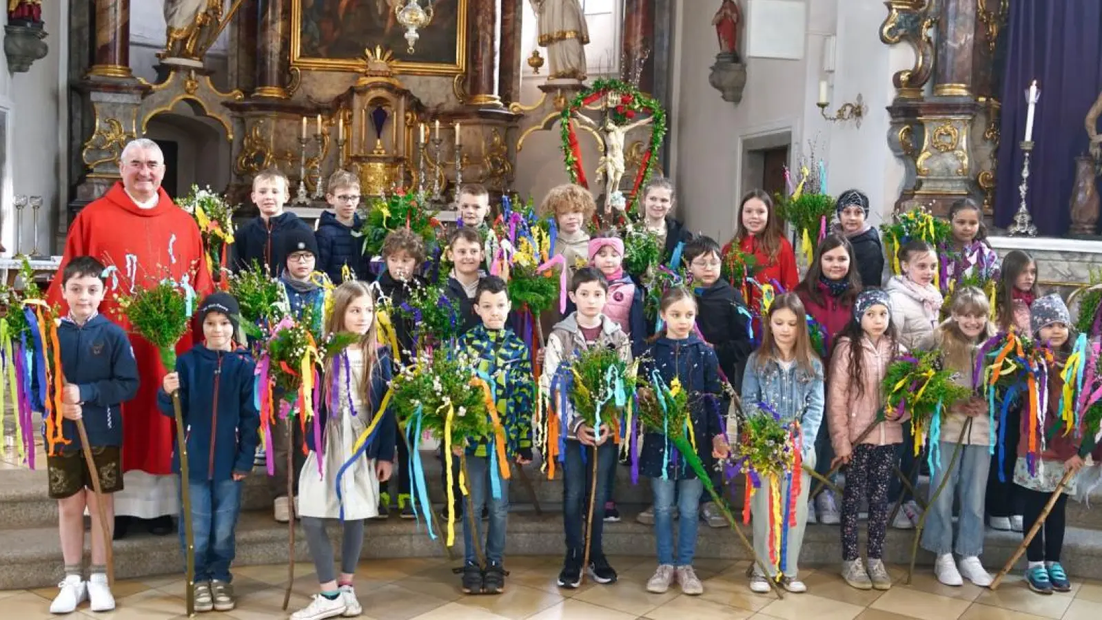 Die Kommunionkinder zeigten mit großer Freude ihre selbstgebastelten Palmbuschen. Links im Bild Pfarrer Alfons Kaufmann. (Bild: Martin Uschold)