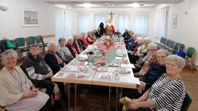 Die Seniorenrunde an der festlich gedeckten Nikolaus-Tafel beim Besuch von Sankt Nikolaus mit Knecht Ruprecht (Mitte) und der Seniorentreffleiterin Elisabeth Schaller (rechts). (Bild: Thomas Helm)